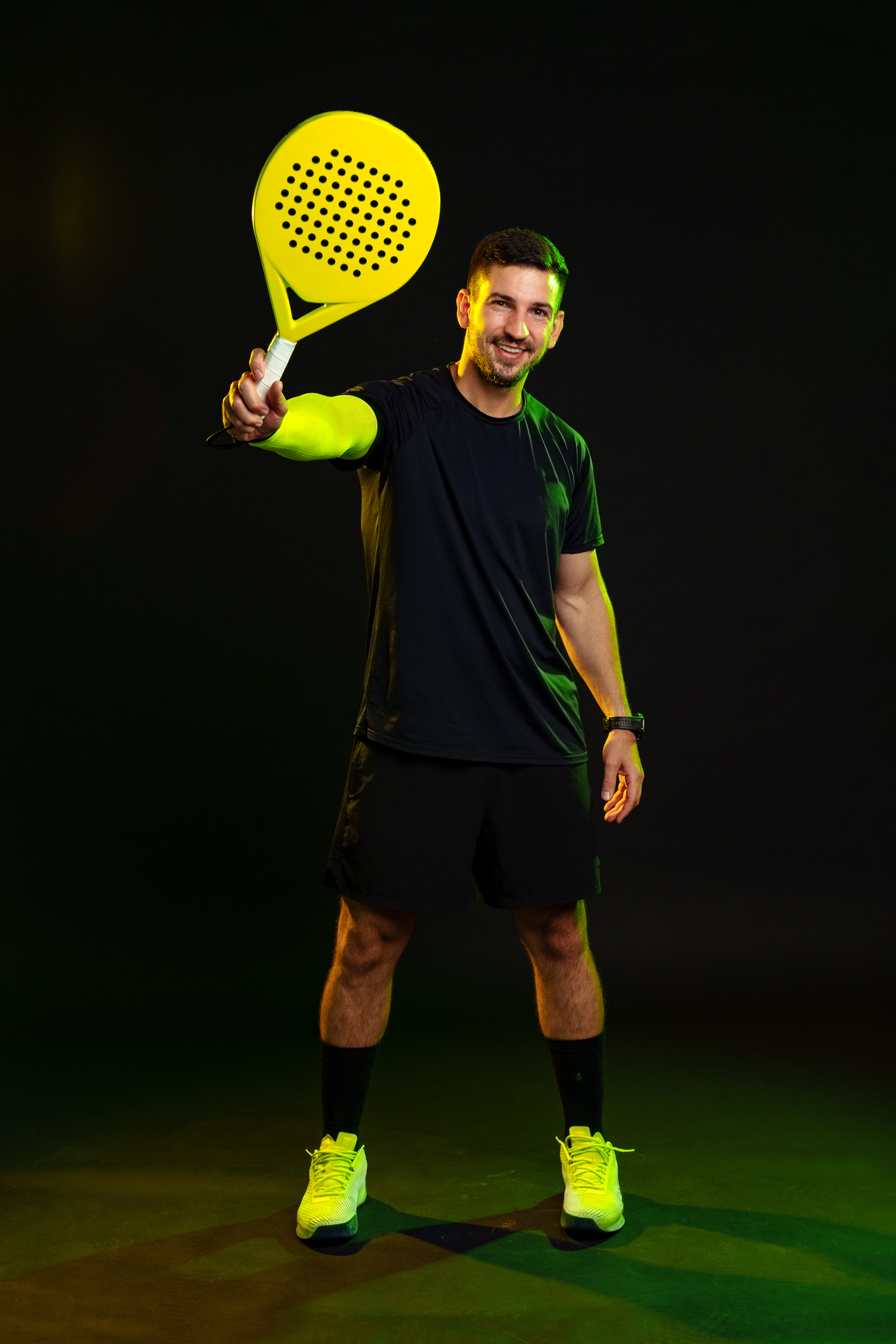 PadelSquad coach in a black tee holding a padel racquet